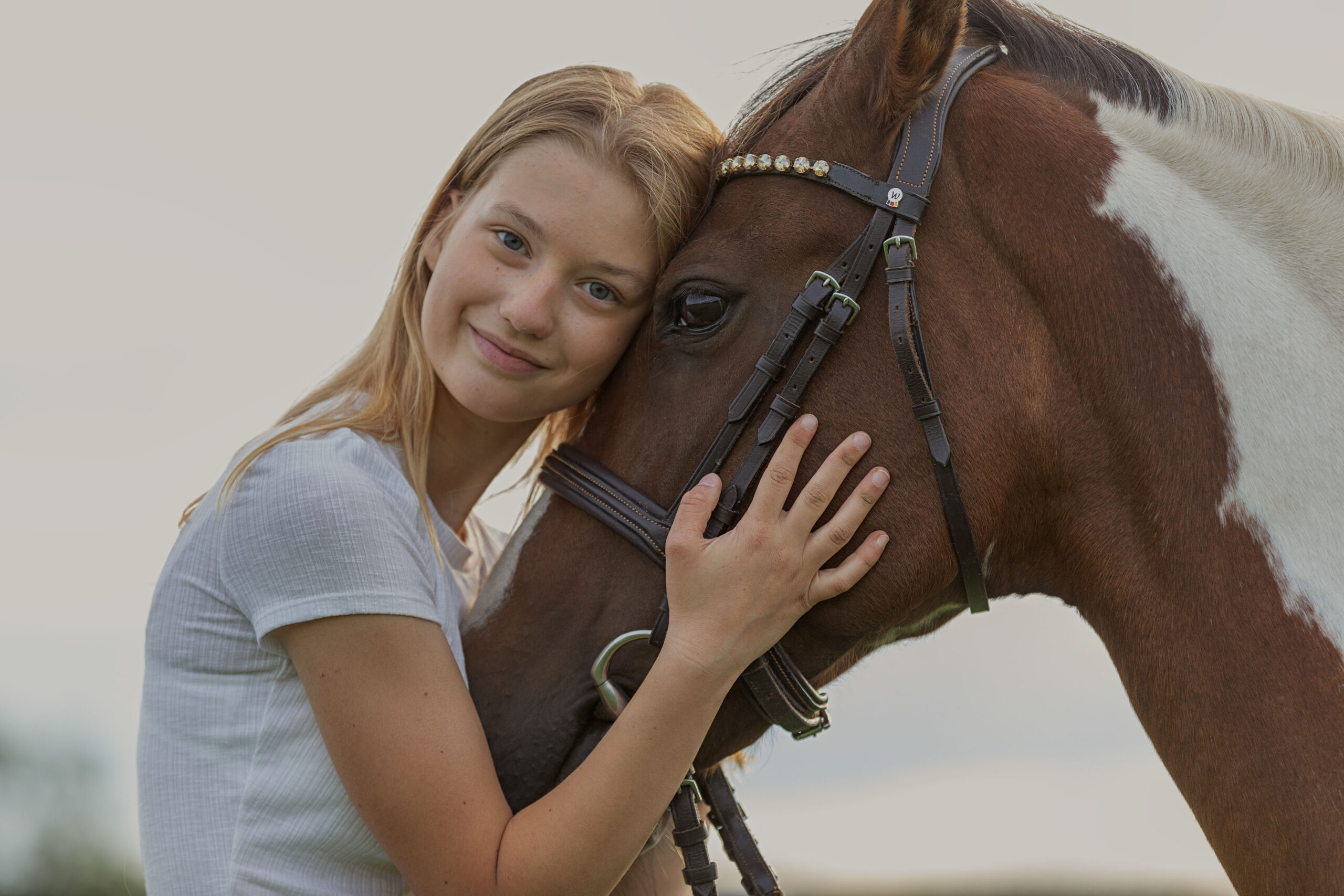 Mädchen schmiegt sich an den Kopf ihres Pferdes, emotionale Pferdeportraits, Pferdemädchen, Horselovers