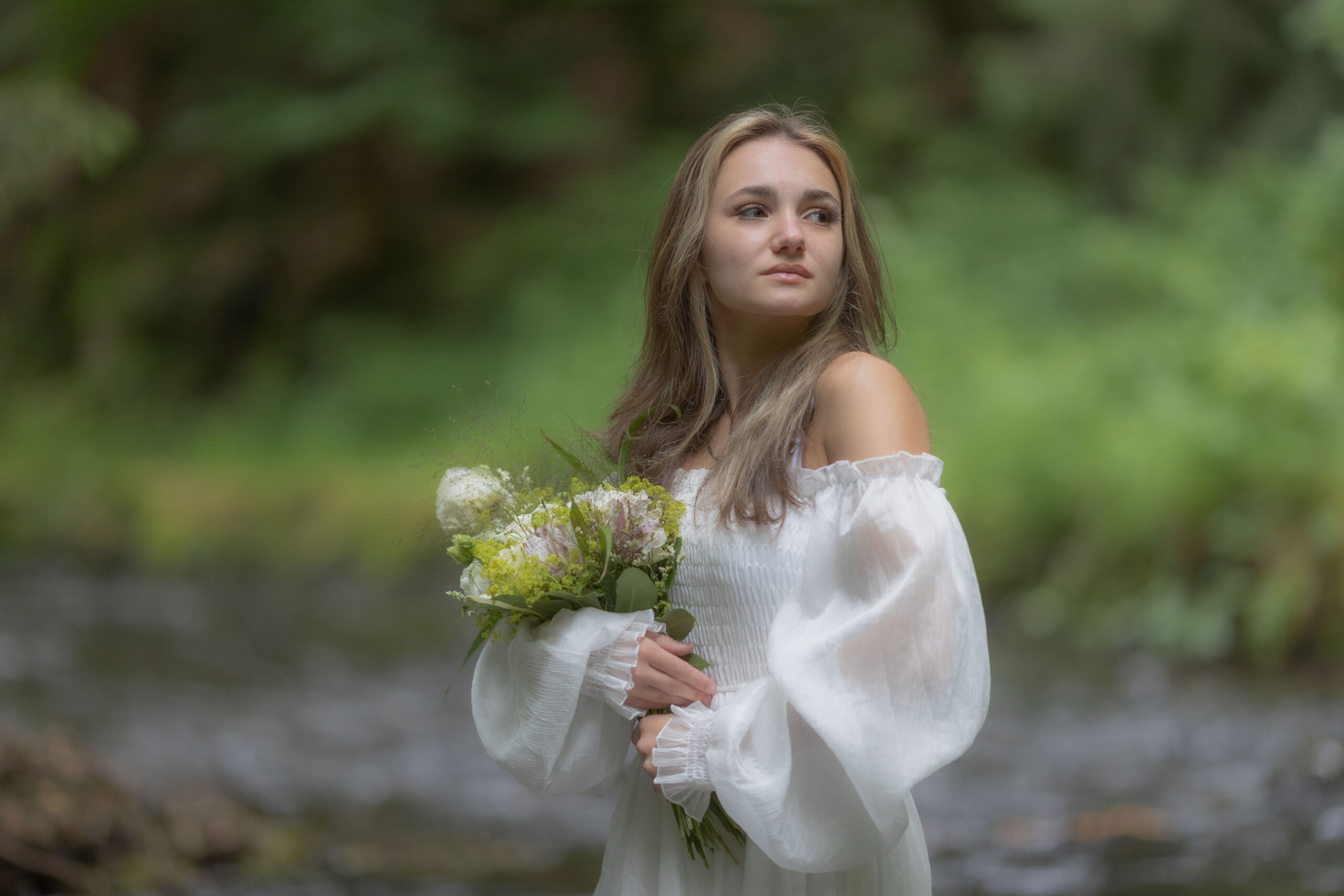 Porträt einer jungen Frau in weißem Kleid und Blumenstrauss im Arm