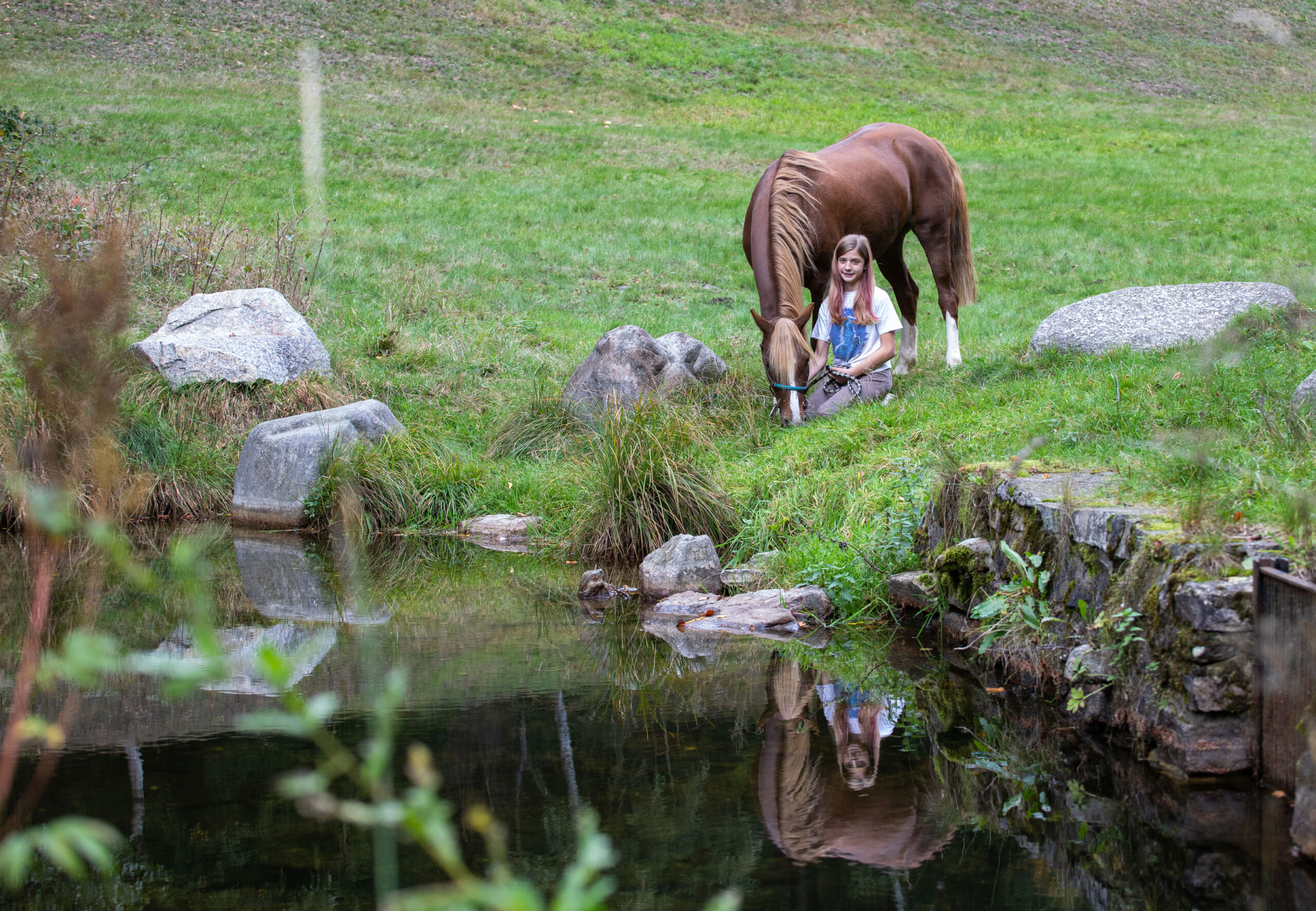 Mädchen mit Pferd an einem Teich
