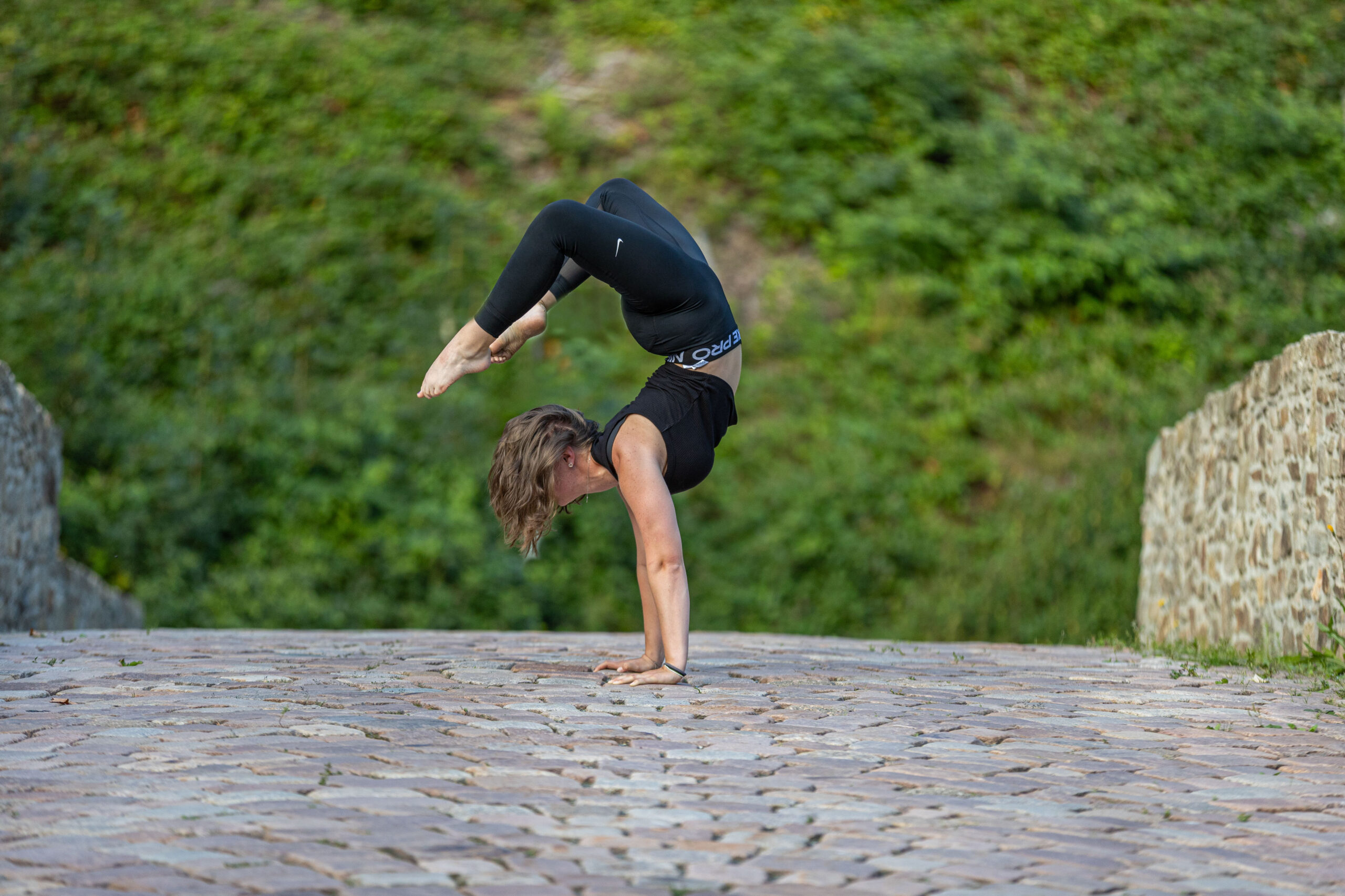 Turnerin macht Handstand auf einer alten Brücke mit Kopfsteinpflaster