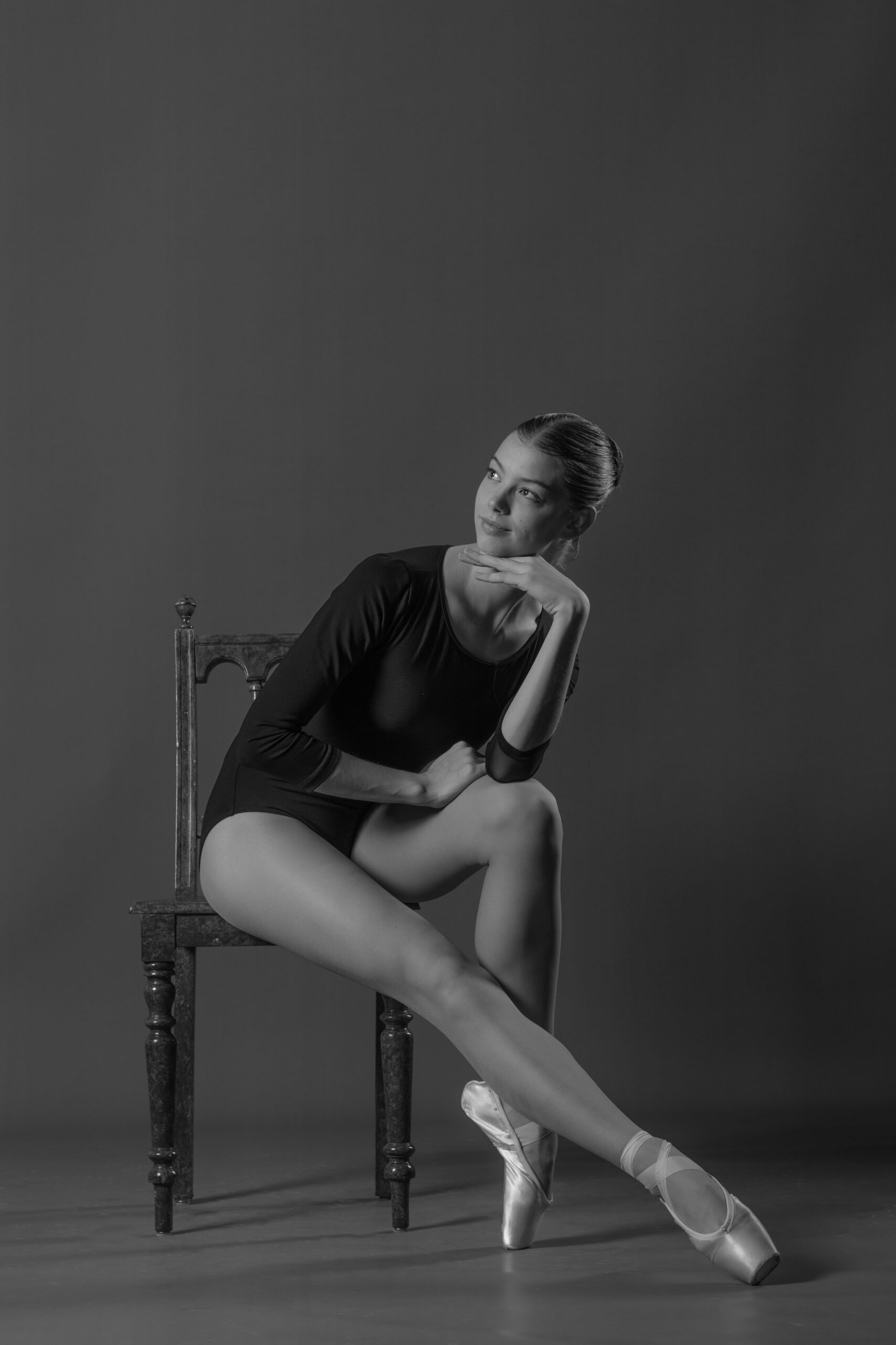Junge Ballerina sitzt auf antikem Stuhl während eines Fotoshootings