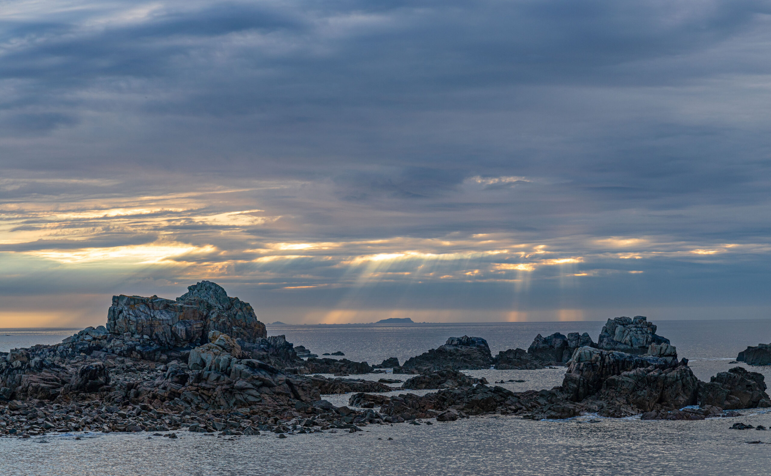 Sonnenstrahlen brechen durch die Wolken an der bretonischen Nordküste