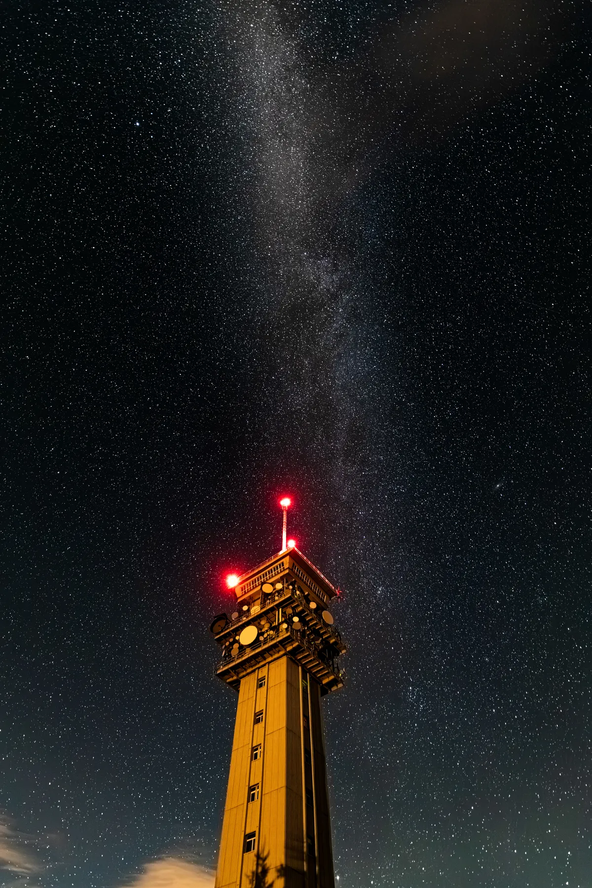 Der Funkturm auf dem Keilberg bei klarer Nacht fotografiert. Über dem Turm spannt sich weit die Milchstraße diagonal durch das Bild