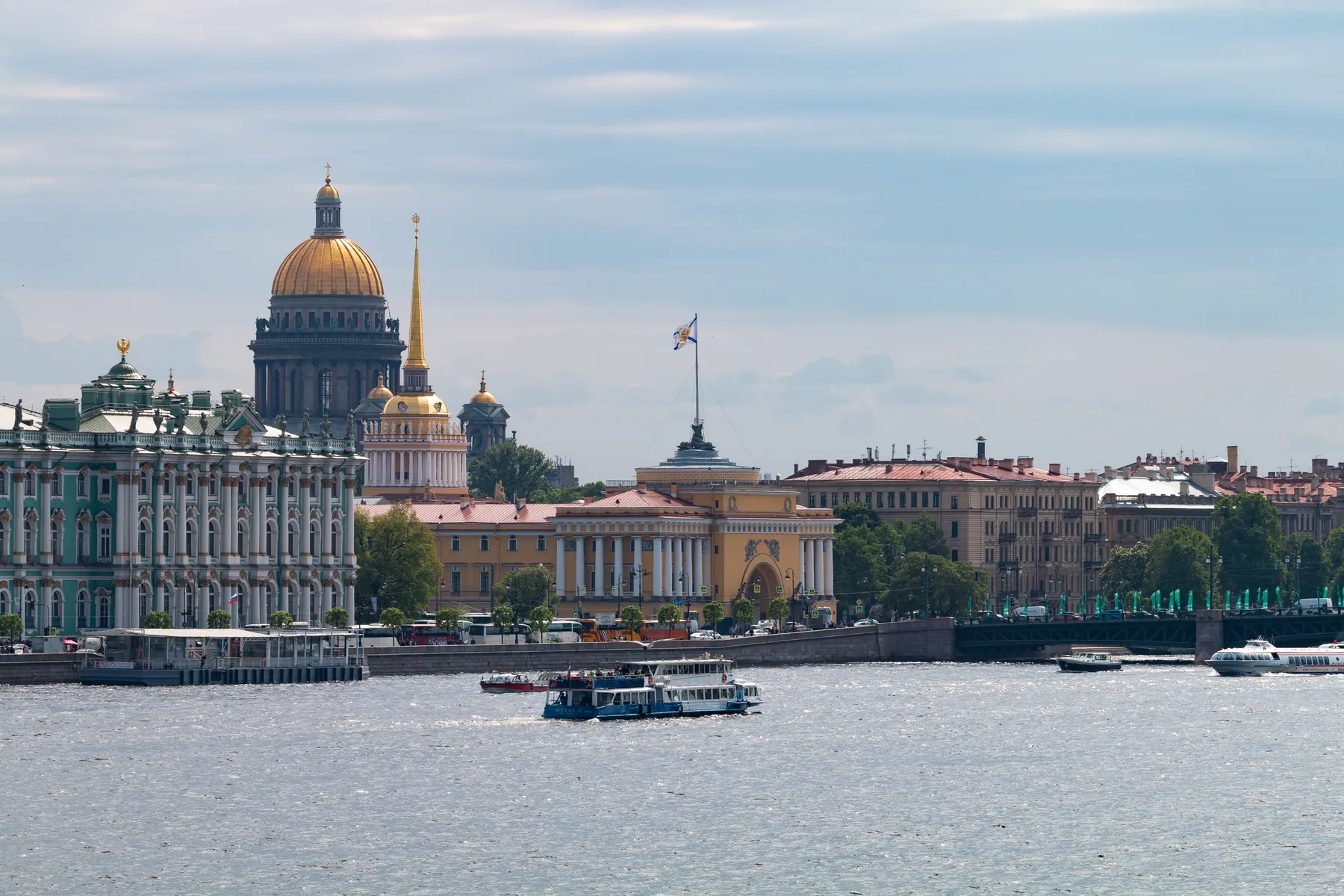 Eine malerische Ansicht von St. Petersburg, Russland, mit der Newa im Vordergrund, Booten auf dem Wasser und ikonischen Wahrzeichen der Stadt wie der goldenen Kuppel der Issacskathedrale , der Admiralität und der Eremitage
