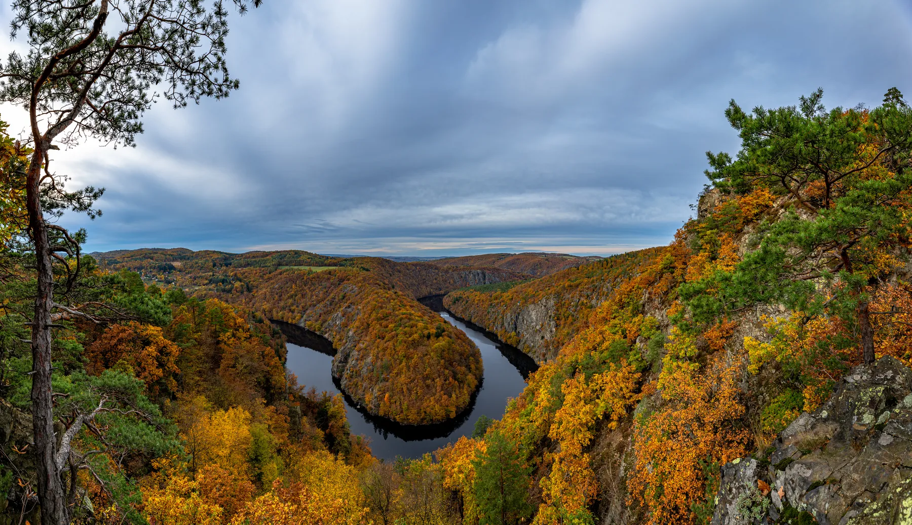 Landschaftsfotografie einer herbstlichen Landschaft mit Fluß, steilen Hängen und einem bedeckten Himmel