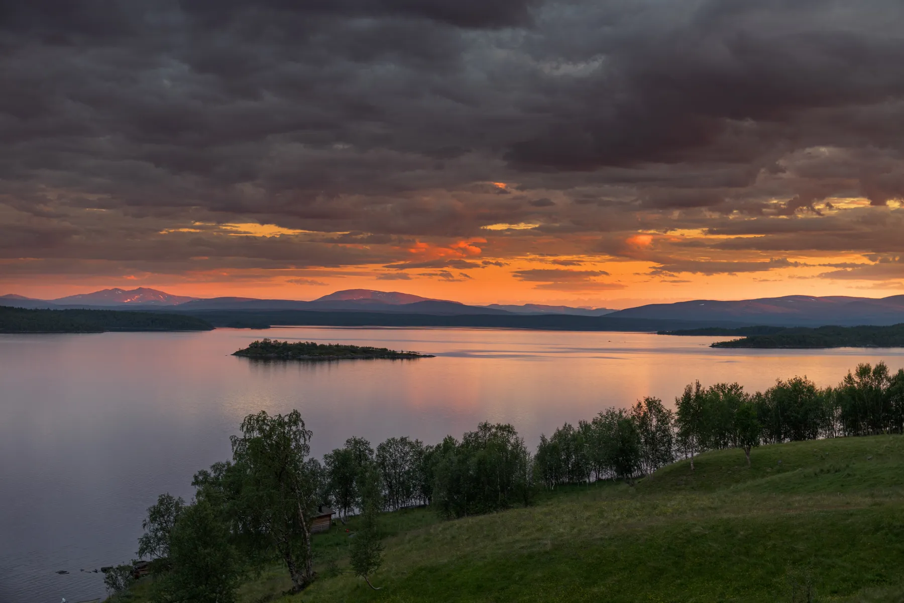 Der See Virisen im schwedischen Lappland mit traumhaften Sonnenuntergang der die Wolken rot einfärbt