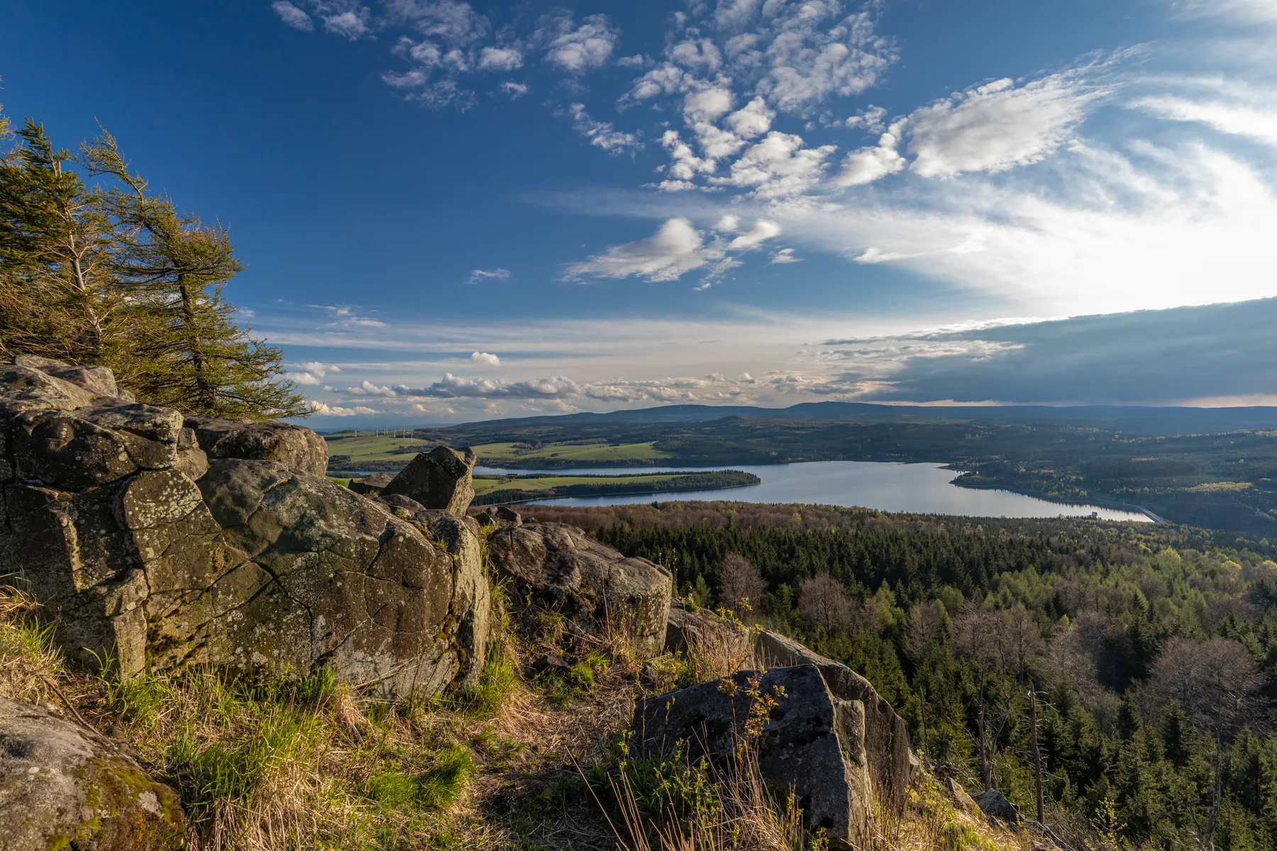 Blick von Felsen über eine Talsperre und bewaldete Hügel im Erzgebirge