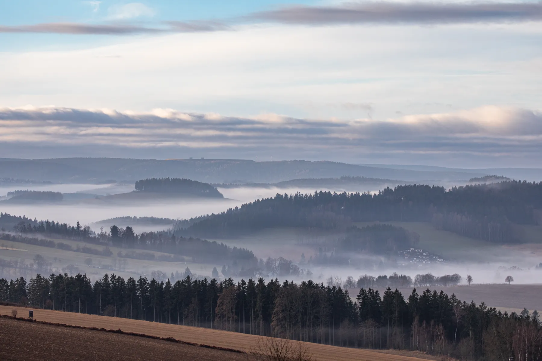 Weite Mittelgebirgslandschaft mit Nebelbändern und ruhiger Fernsicht