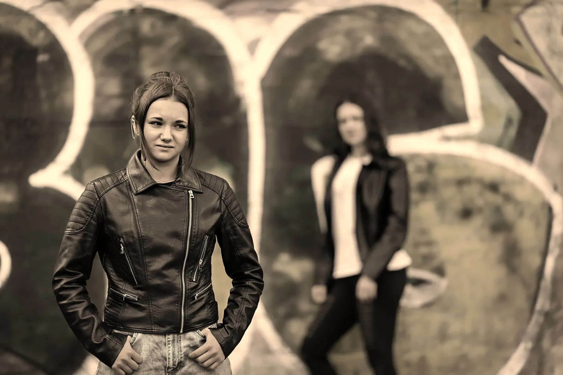 Portraitfotografie zweier junger Frauen vor einer Graffitiwand in Sepiatönen
