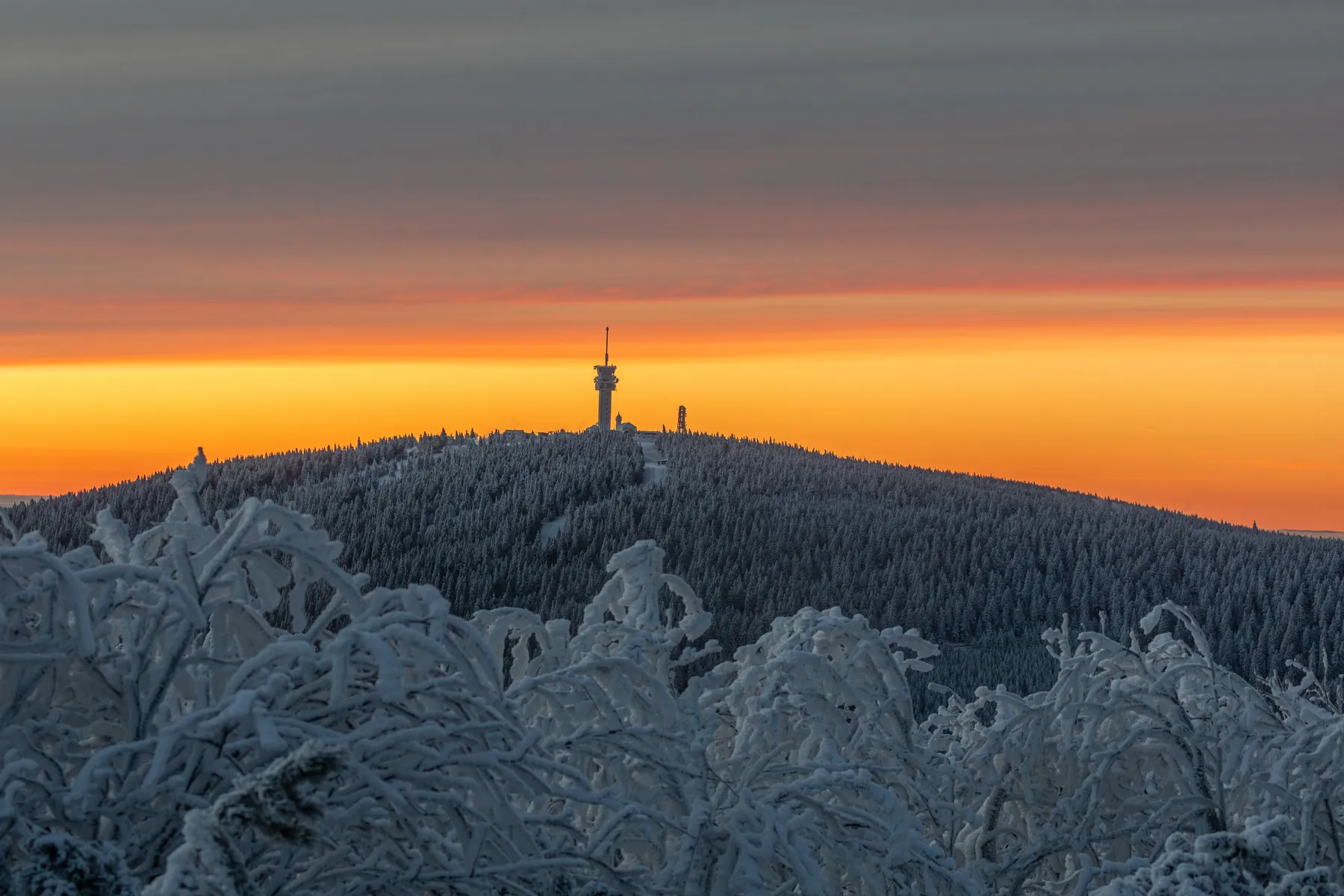 Verschneiter Keilberg mit Sendeturm vor intensivem Morgenhimmel im Erzgebirge