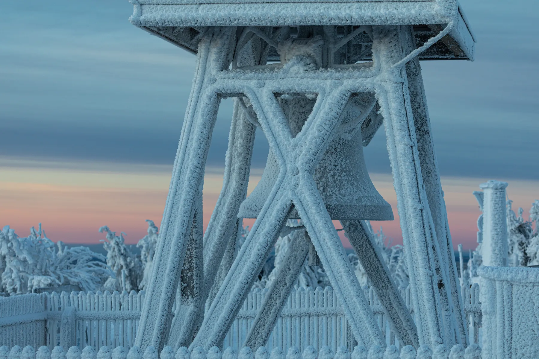 Vereiste Friedensglocke auf dem Fichtelberg im Erzgebirge mit Raureif bei ruhigem Winterlicht