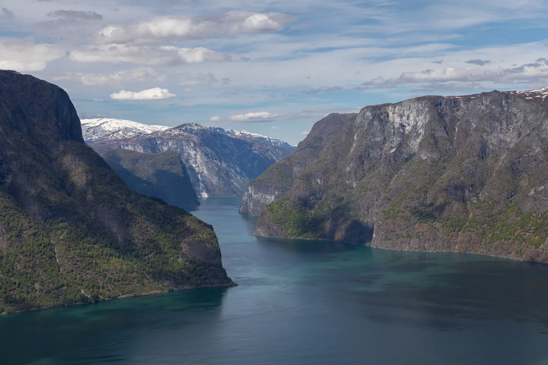 Landschaftsfotografie des Aurlandsfjordes mit steilen bewachsenen Felswänden und einem bewölkten Himmel