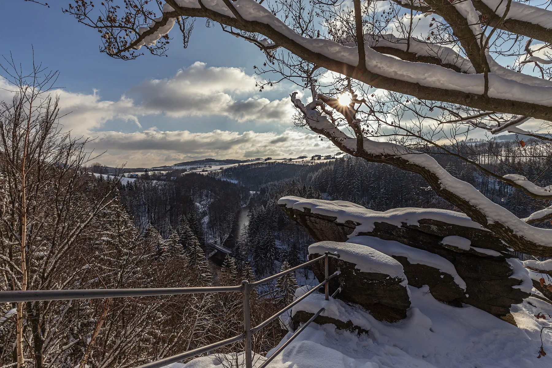 Aussichtspunkt Brückenklippe in der Wolkenstein Schweiz mit schneebedeckten Felsen und Blick über bewaldetes Wintertal