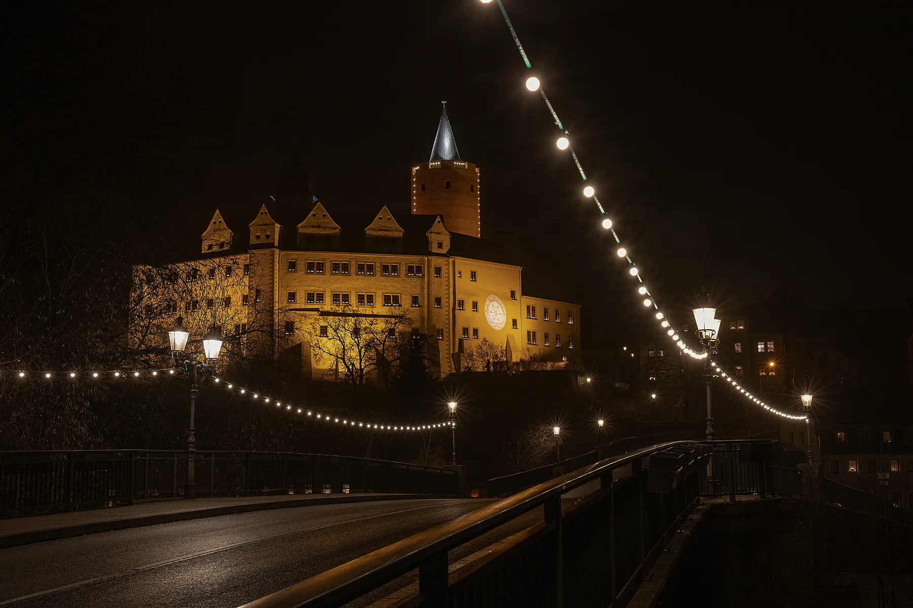 Nächtliche Aufnahme vom Schloss Wildeck in Zschopau mit Brücke und Lichterketten
