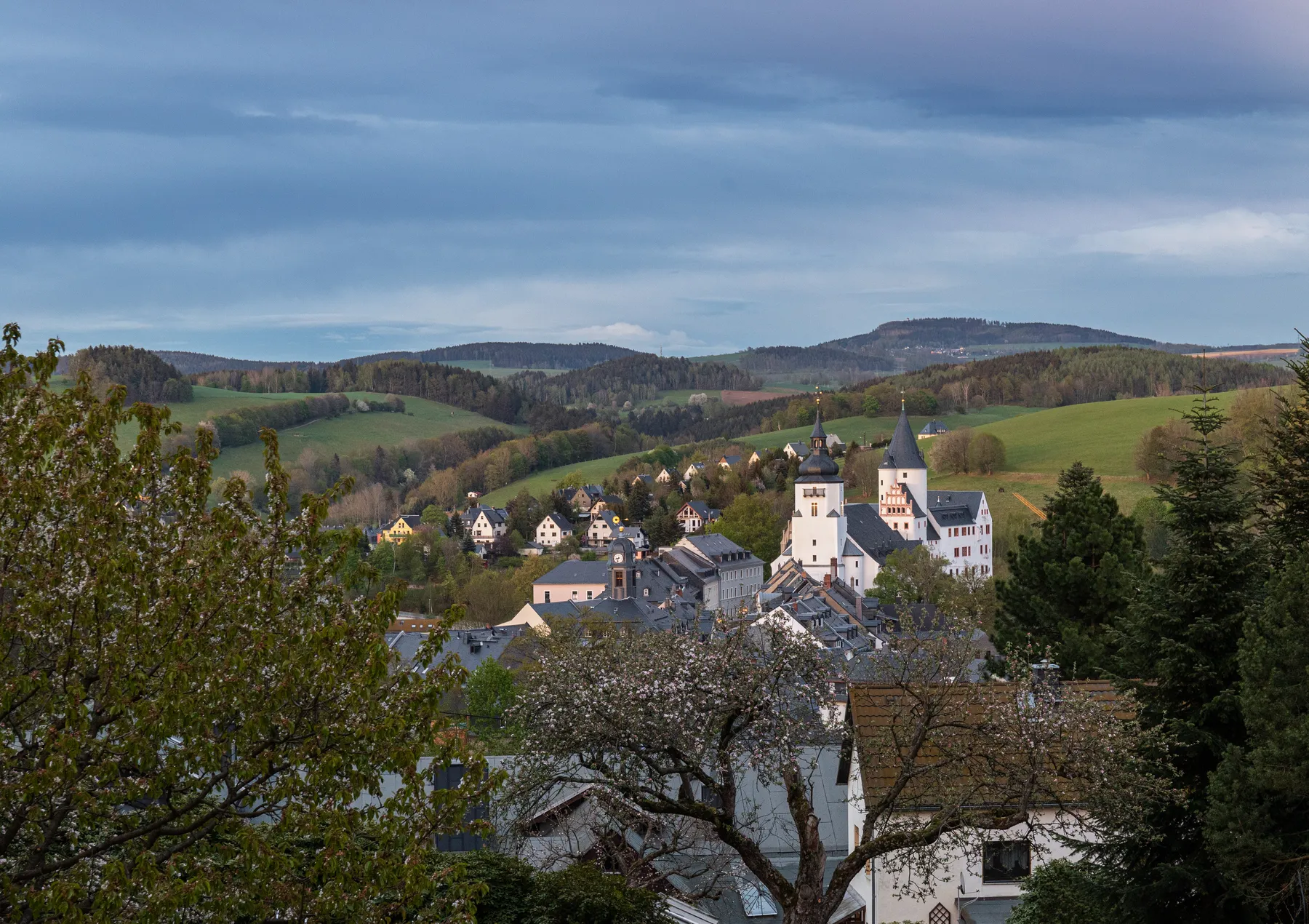 Blick auf Schwarzenberg mit markanter Kirche und gleichnamigen Schloß, umgeben von sanften Hügeln und grüner Landschaft
