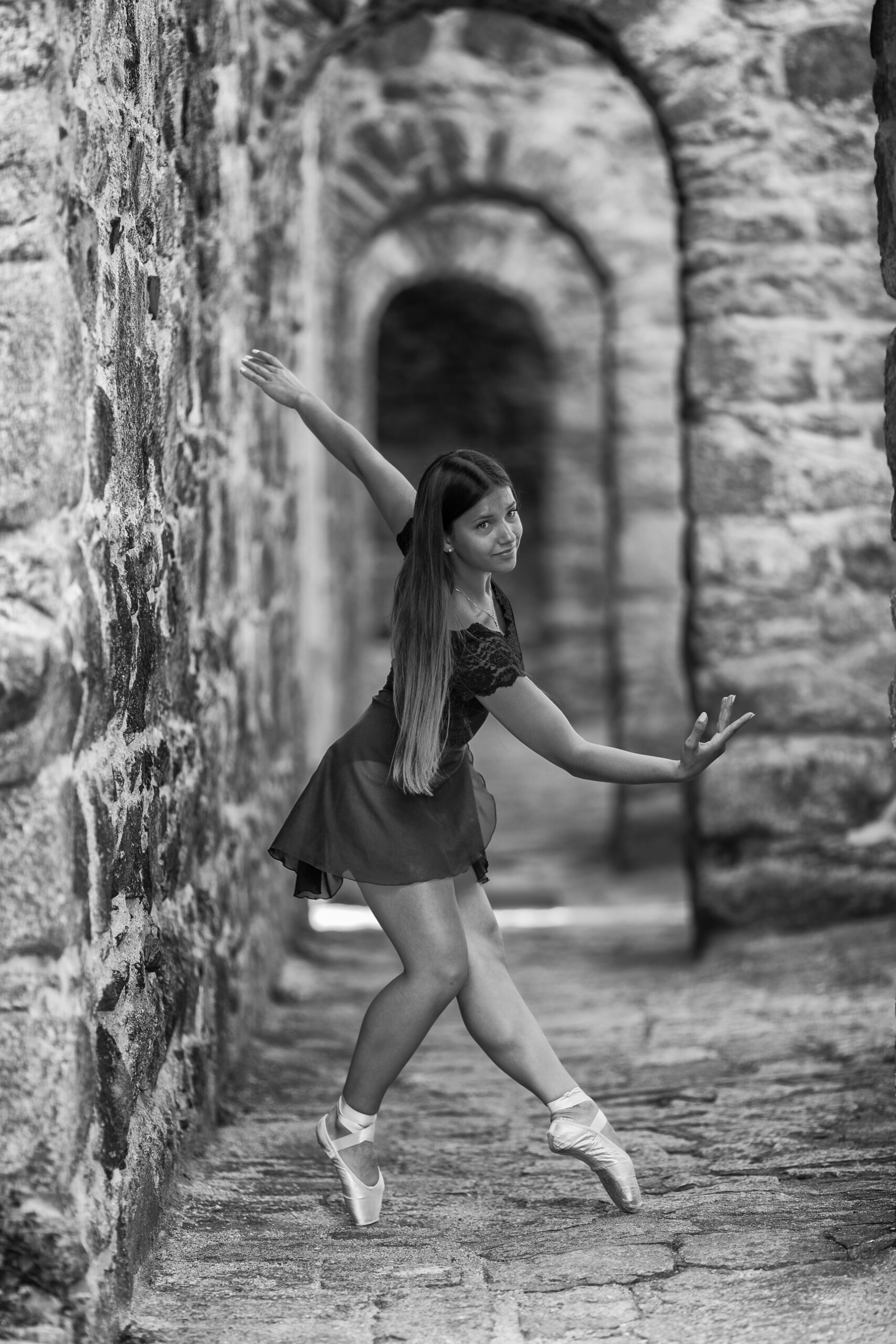 Schwarz weiß Foto einer Ballerina die in Ballettpose in einem alten Gebäude steht