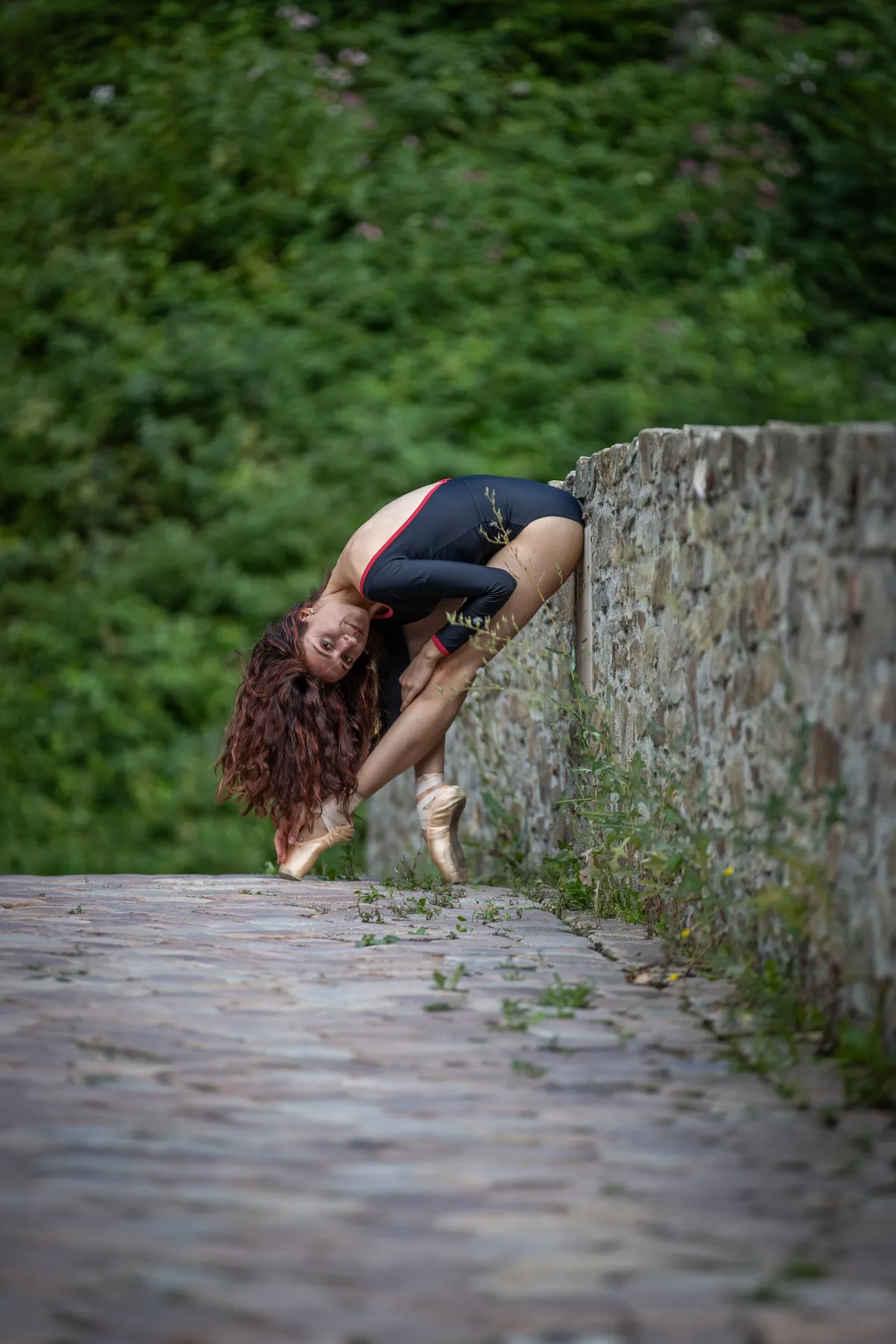 Balletttänzerin auf Spitzenschuhen an einer alten Steinmauer