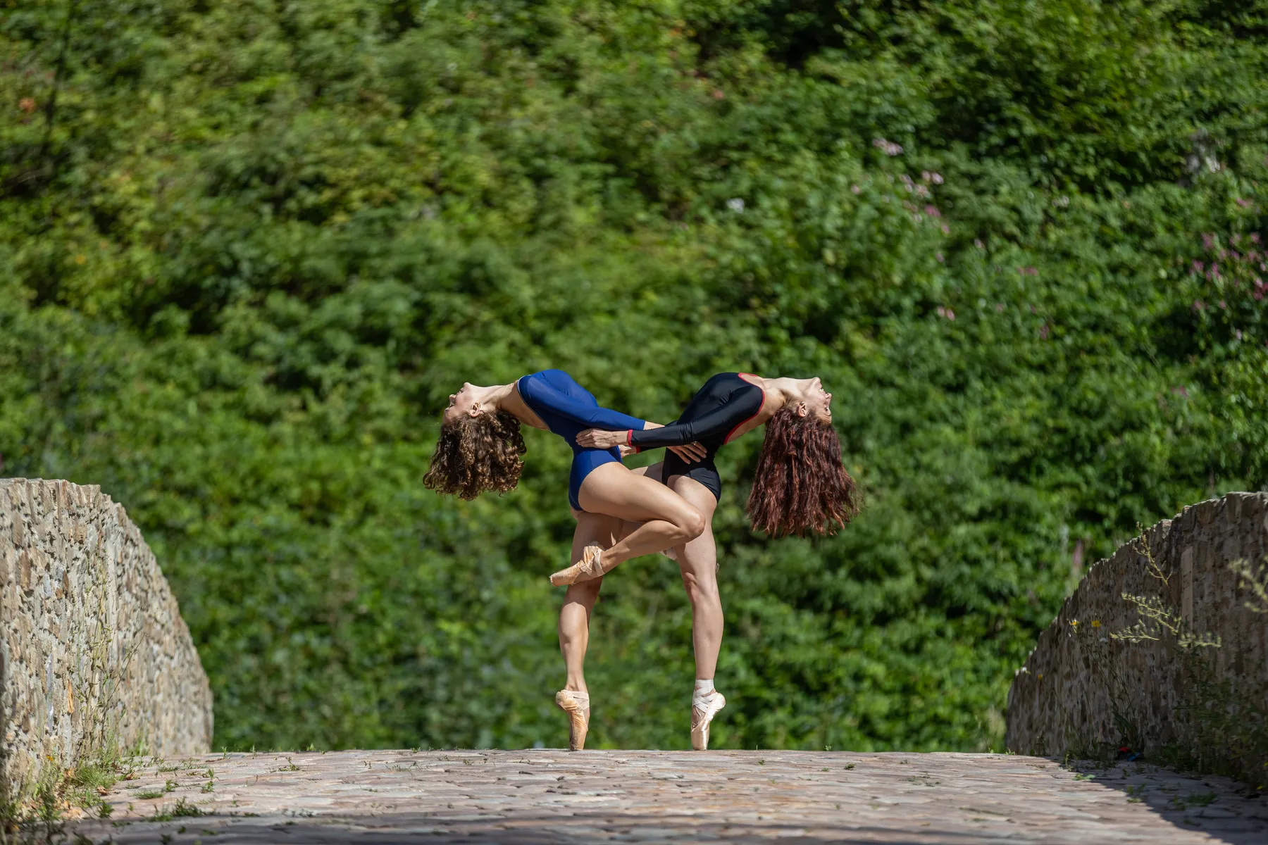 Zwei Balletttänzerinnen auf Spitzenschuhen auf einer alten Brücke
