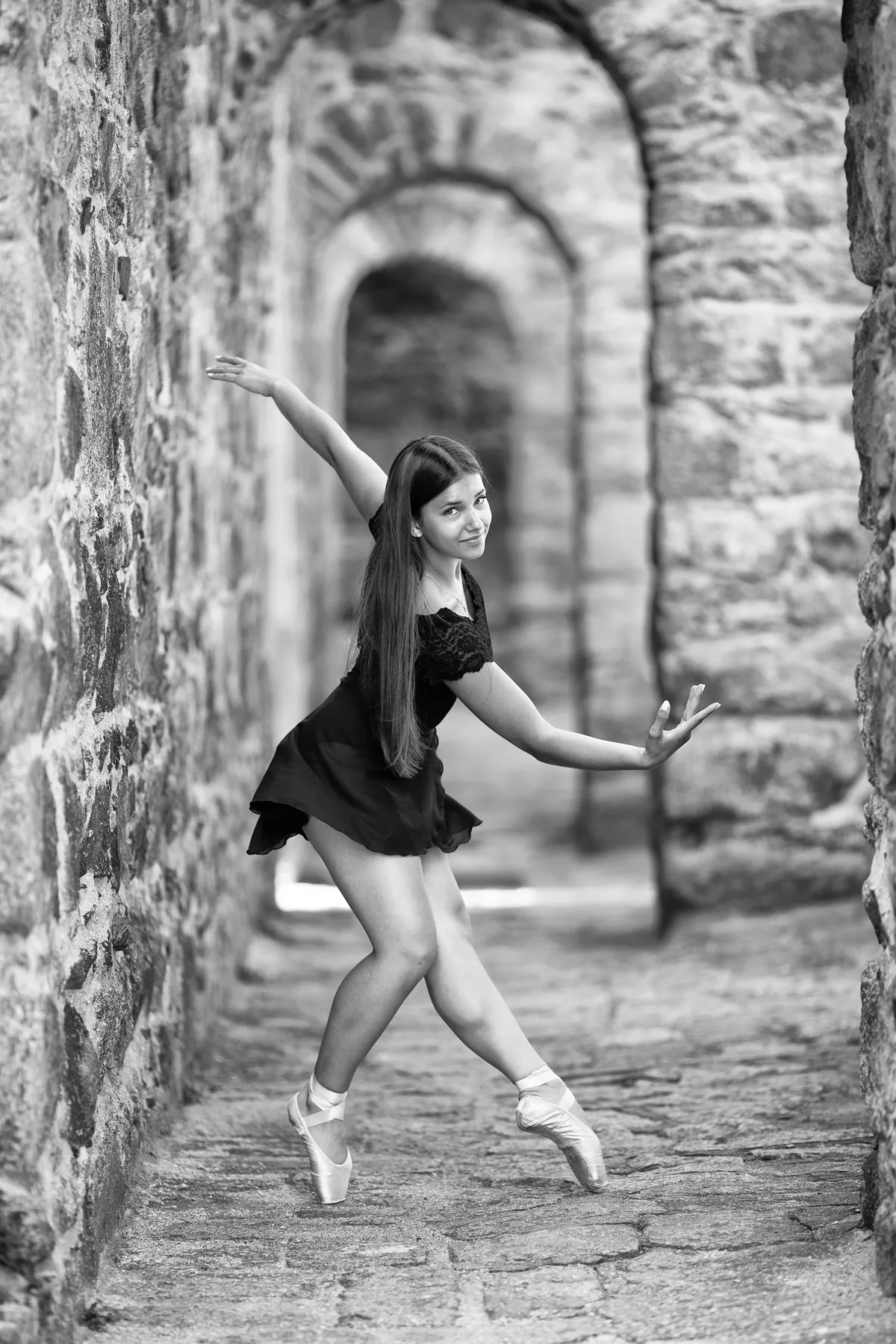 Schwarz weiß Foto einer Ballerina die in Ballettpose in einem alten Gebäude steht